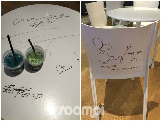 Two fruity artist ades from the SMTOWN Cafe menu on a wooden signed table featuring a Super Junior blue lemonade ade and a SHINee green apple ade served in clear tall glasses
