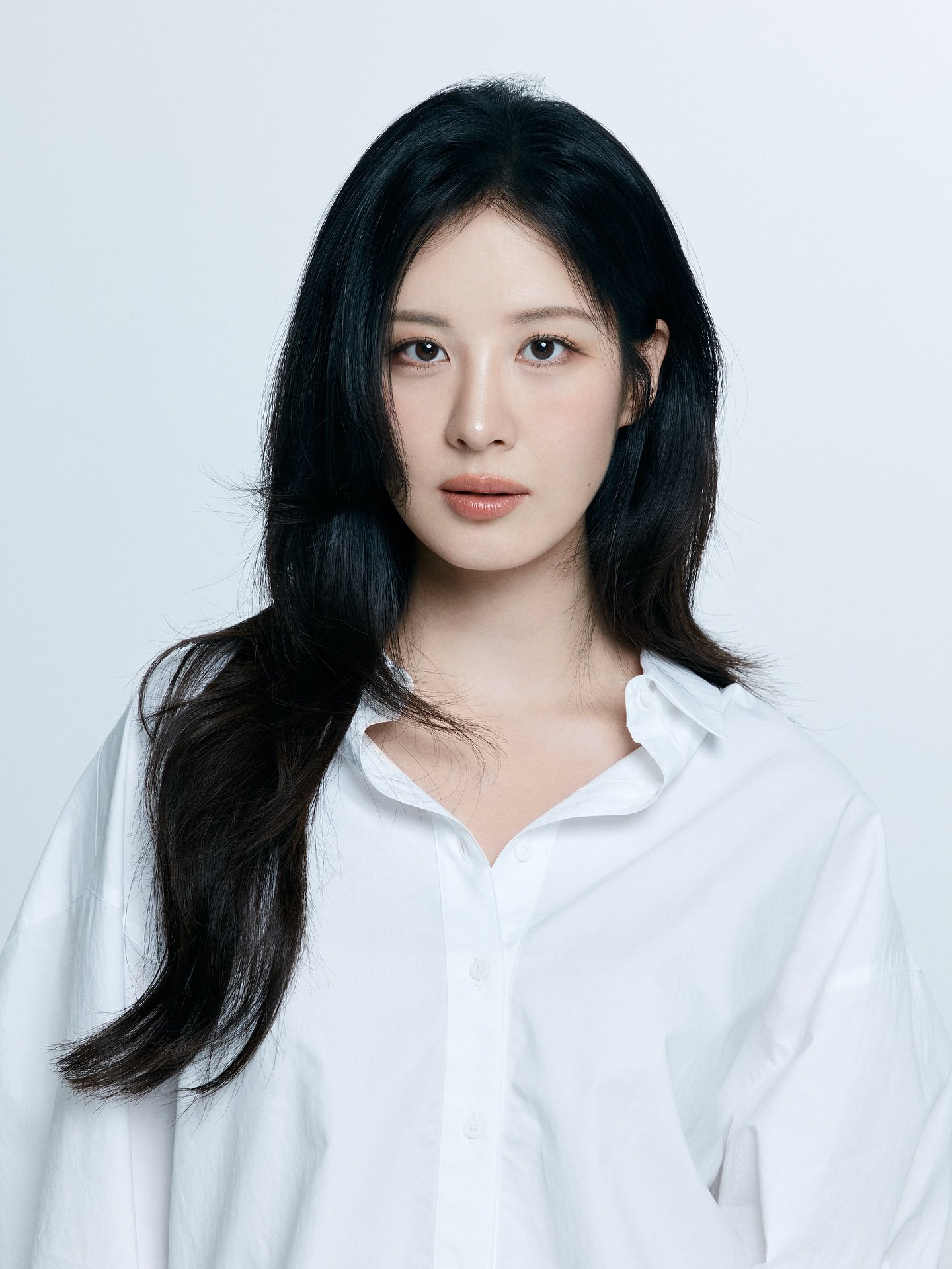 Seohyun in a white shirt with long black hair, looking serene and pure.