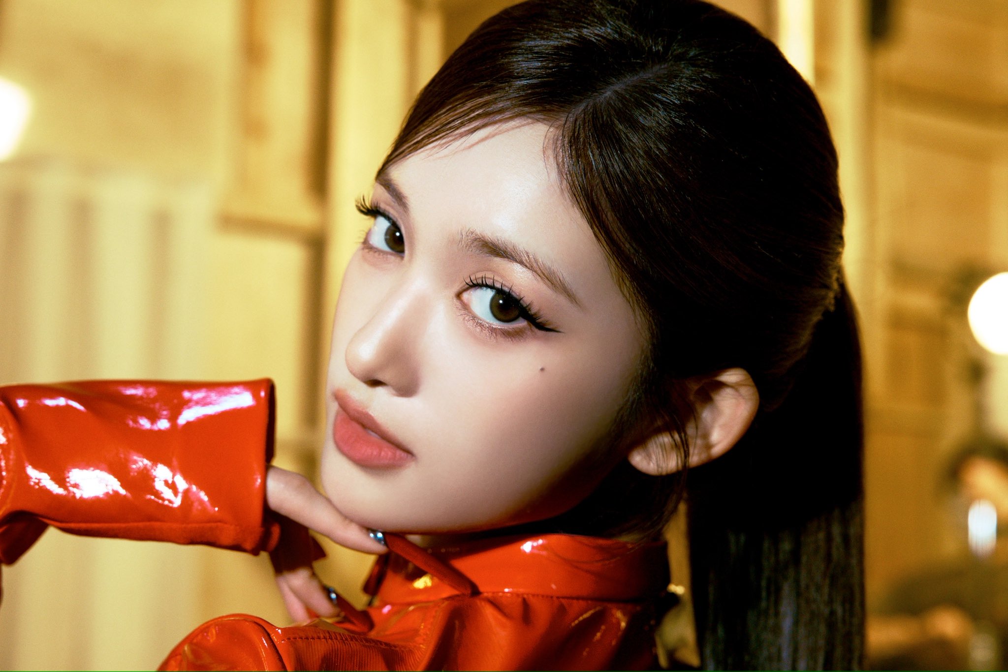 IVE member holding a red-gloved hand near her face